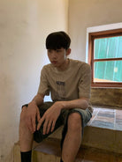 NeverSeez Garment Dyed Puppet Print Tee in Khaki - On Male Model