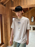NeverSeez Garment Dyed Puppet Print Tee in Khaki - On Male Model