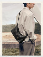 Songmont Vegetable Tanned Lambskin Pillow Hobo in Black - On Male Model